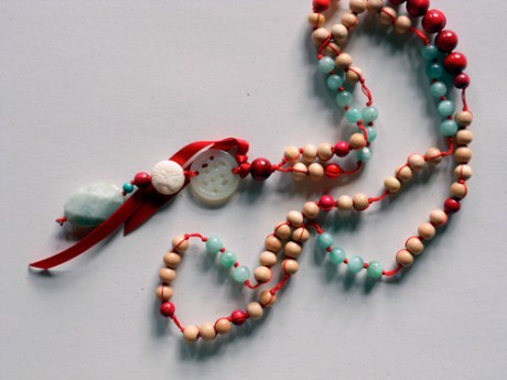 A long piece featuring light-coloured wooden beads with accents of red and aqua.