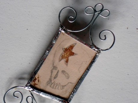 Lovely little skull and star drawing between glass and copper with wire embellishments.