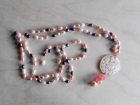 Pink, peach, white and purple/grey freshwater pearls with a mother-of-pearl dragon pendant and an accent of cherry quartz.