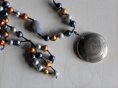 A close up of the engraved pendant. It may be silver or pewter. 