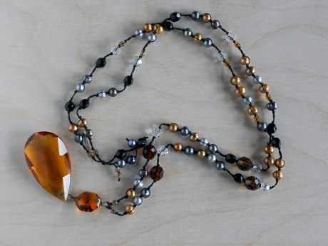 An amber-coloured chandelier crystal hanging from pearls of amber, siilver and grey colours with amber- and clear-coloured faceted glass. © Firehorse Designs