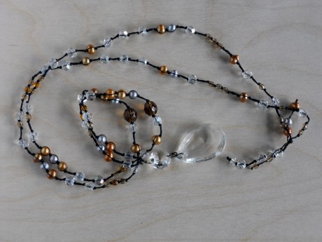 A single clear crystal chandelier drop hangs from amber-and silver-coloured pearls and clear- and amber-coloured glass. © Firehorse Designs